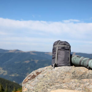 Sleeping bag and camping mat on mountain peak, space for text