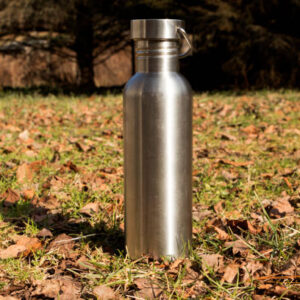 A vertical shot of metallic tumbler on the ground under sunlight